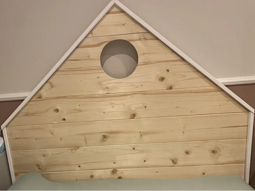 Holzkopfteil eines Bettes in Hausform