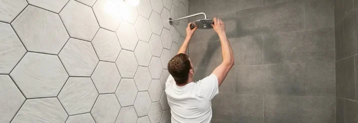 Person montiert Duschkopf.