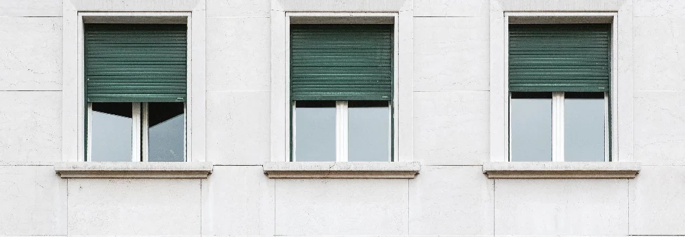 Drei Fenster mit grünen Rollläden