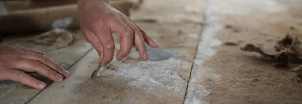 Hände entfernen Teppichkleber von Holzboden