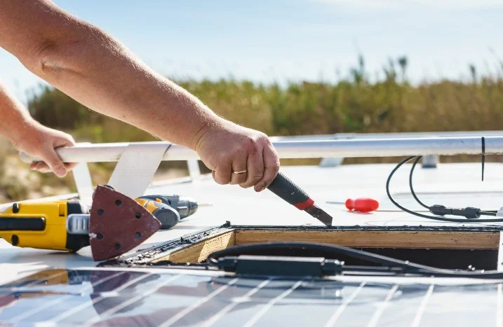 Person schneidet mit Cuttermesser in Wohnmobil-Dach