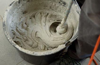 Fliesenkleber für Natursteine anrühren In einem großen Eimer wird Fliesenkleber angerührt.