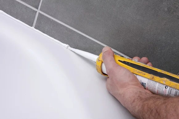 Hand trägt Dichtmittel mit Kartusche auf