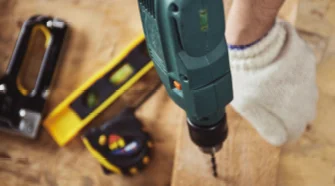 Hand bohrt mit Bohrmaschine in Holz