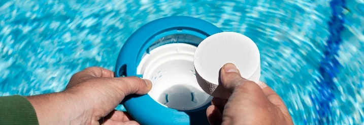 Person befüllt schwimmenden Chlorspender