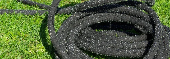 Schwarzer Gartenschlauch auf Rasen