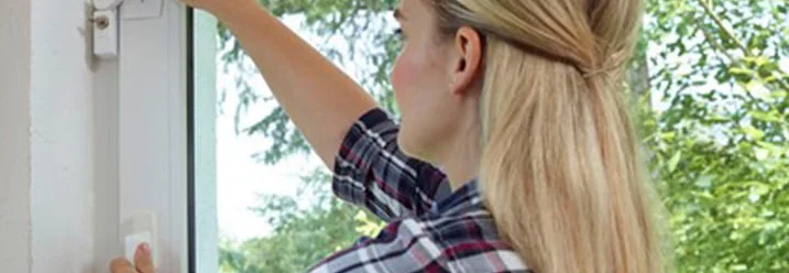 Person schließt Fenster mit Fenstergriff