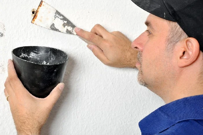 Person verspachtelt Loch in Wand