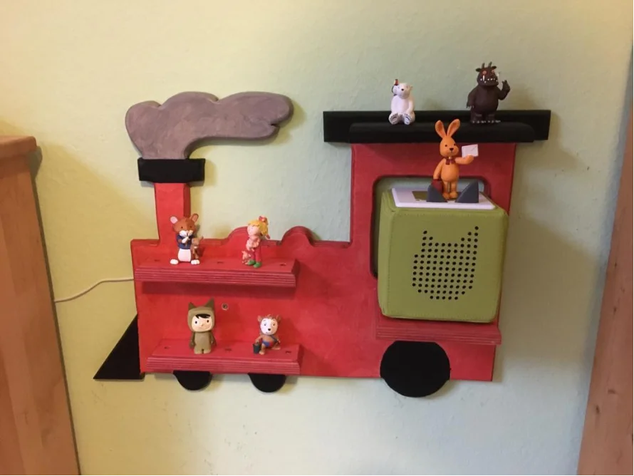 Rotes Wandregal in Form einer Lokomotive mit Spielfiguren