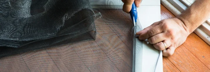 Person schneidet Fliegengitter mit Schere zu