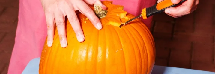 Person schnitzt mit Messer Kürbis