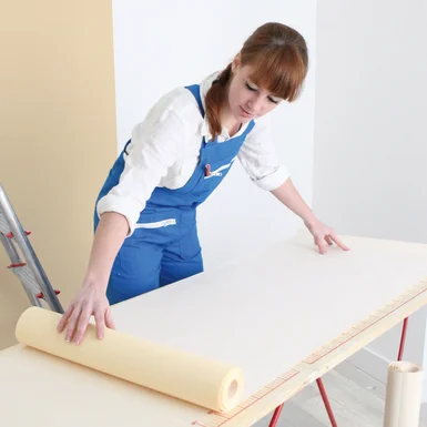 Person rollt Tapete auf Tisch aus