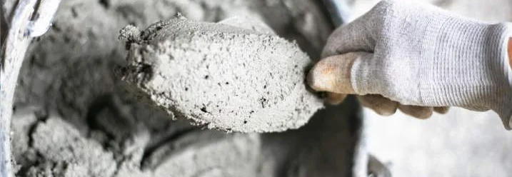 Hand mit Kelle hebt Zement aus Eimer