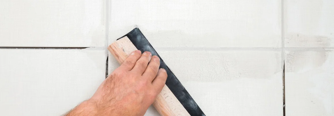 Hand fugt Fliesen mit Gummi