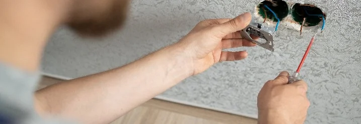 Person montiert Steckdose mit Schraubendreher.