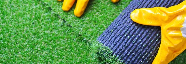 Person rollt Kunstrasen aus