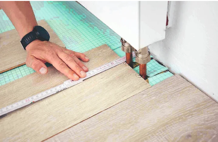 Person misst Laminat mit Zollstock aus