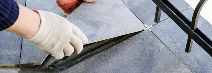 Person verlegt graue Fliesen