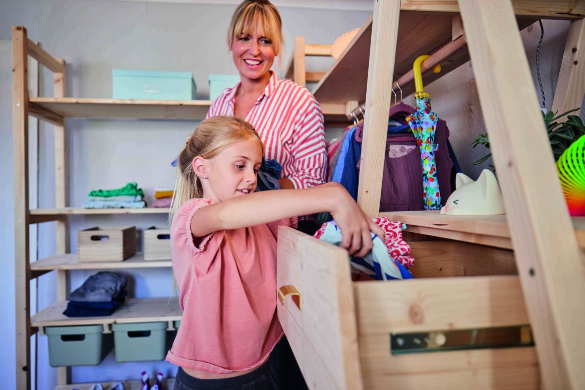 Kind räumt Kleidung in einem Schrank auf