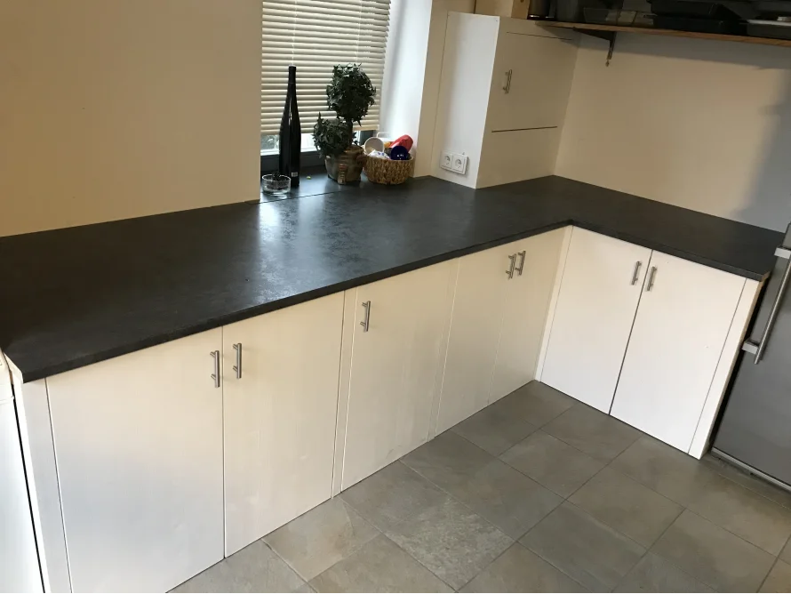 Küchenzeile mit dunklen Arbeitsplatten und weißen Schränken
