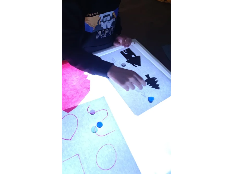 Kind spielt mit Formen auf Leuchttisch