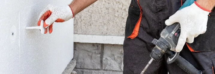 Person befestigt Dämmung mit Bohrer
