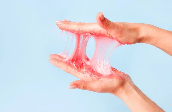 Hände spielen mit pinkem Schleim.