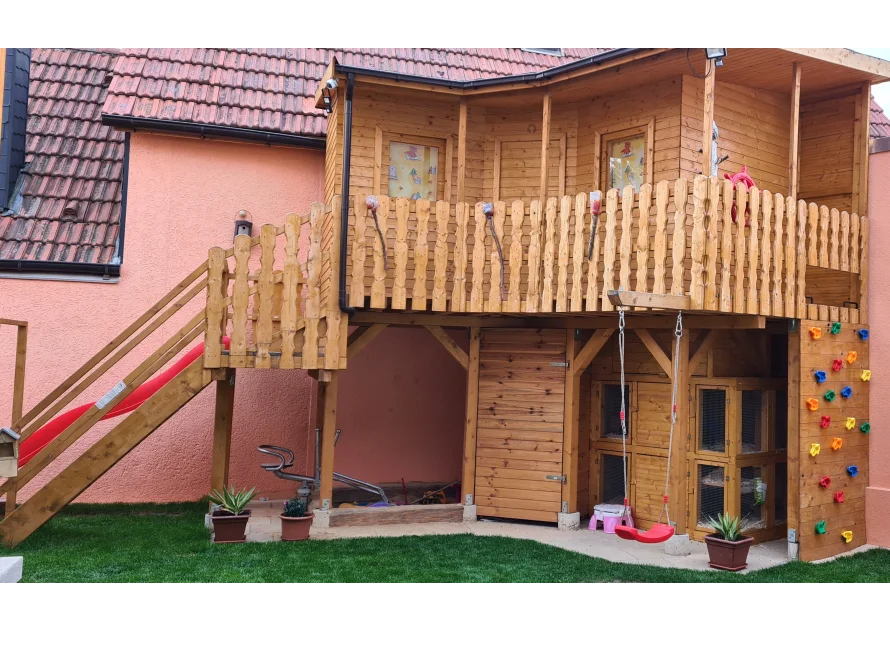 Ein großes Spielhaus aus Holz mit Rutsche und Schaukel.