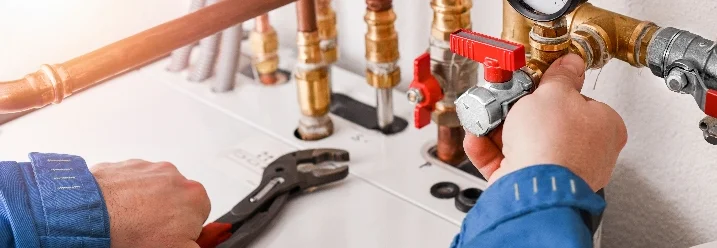 Person repariert Rohre mit Rohrzange