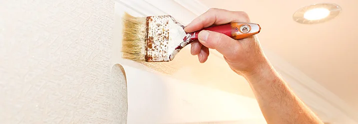 Person streicht Tapete an Wand