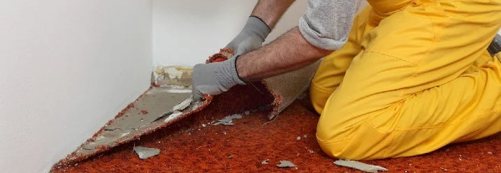 Person entfernt Teppich mit Handschuhen