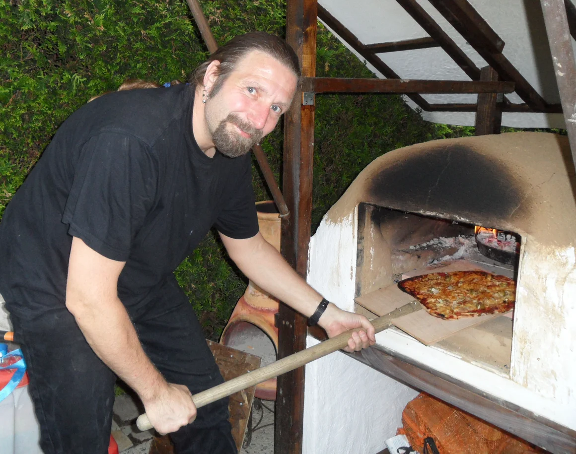 Person schiebt Pizza mit Pizzaschieber in Ofen