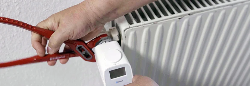Person montiert Thermostat an Heizung