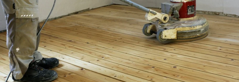 Person schleift Holzboden mit Schleifmaschine