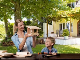 Zwei Personen bauen ein Vogelhaus mit Hammer