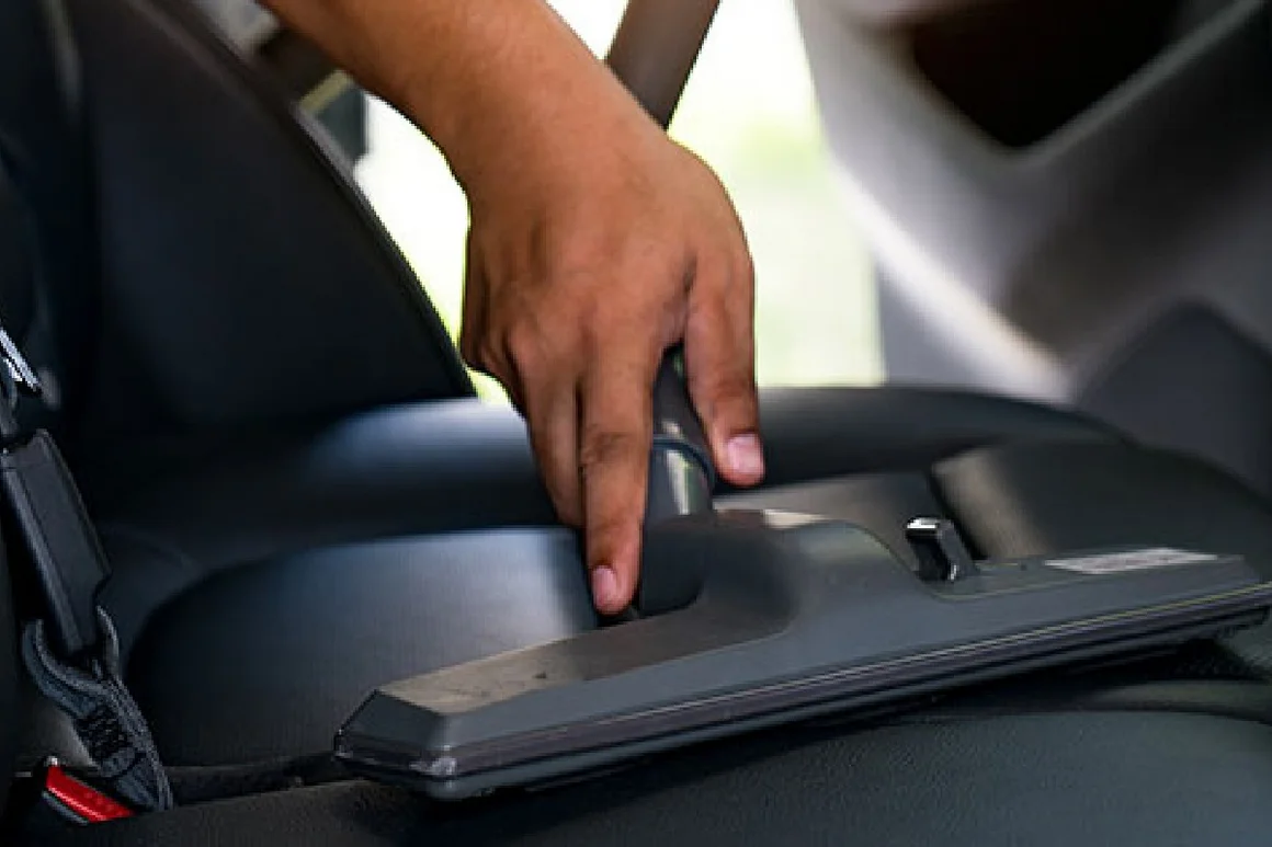 Hand saugt Autositz mit Staubsauger