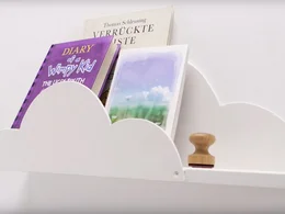 Ein weißes Bücherregal in Wolkenform an der Wand.
