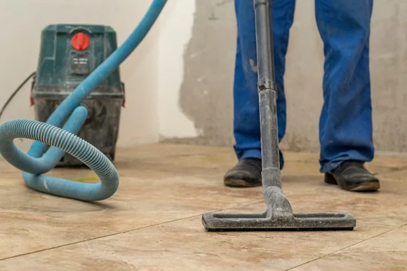 Person saugt einen Fliesenboden mit einem Industriesauger.