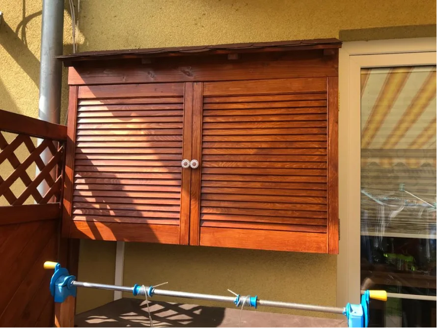 Holzschrank mit Lamellentüren an Hauswand