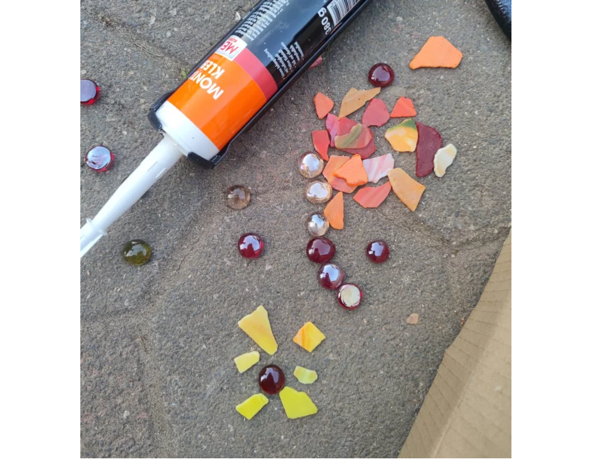 Eine Kartuschenpresse mit bunten Mosaiksteinen auf einem Steinboden.