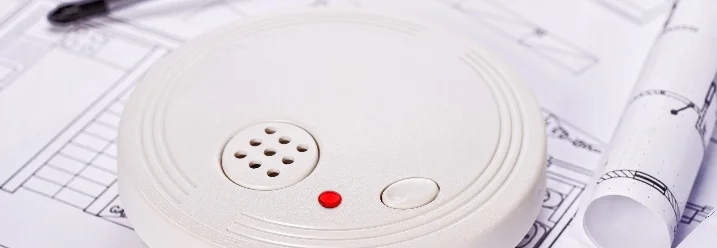 Rauchmelder und Schraubenzieher auf Bauplan