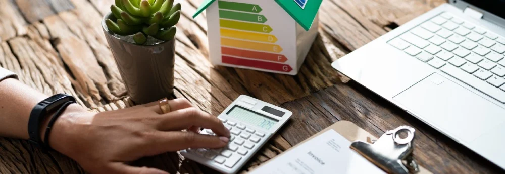 Person berechnet die Energieeffizienz eines Hauses mit einem Taschenrechner.