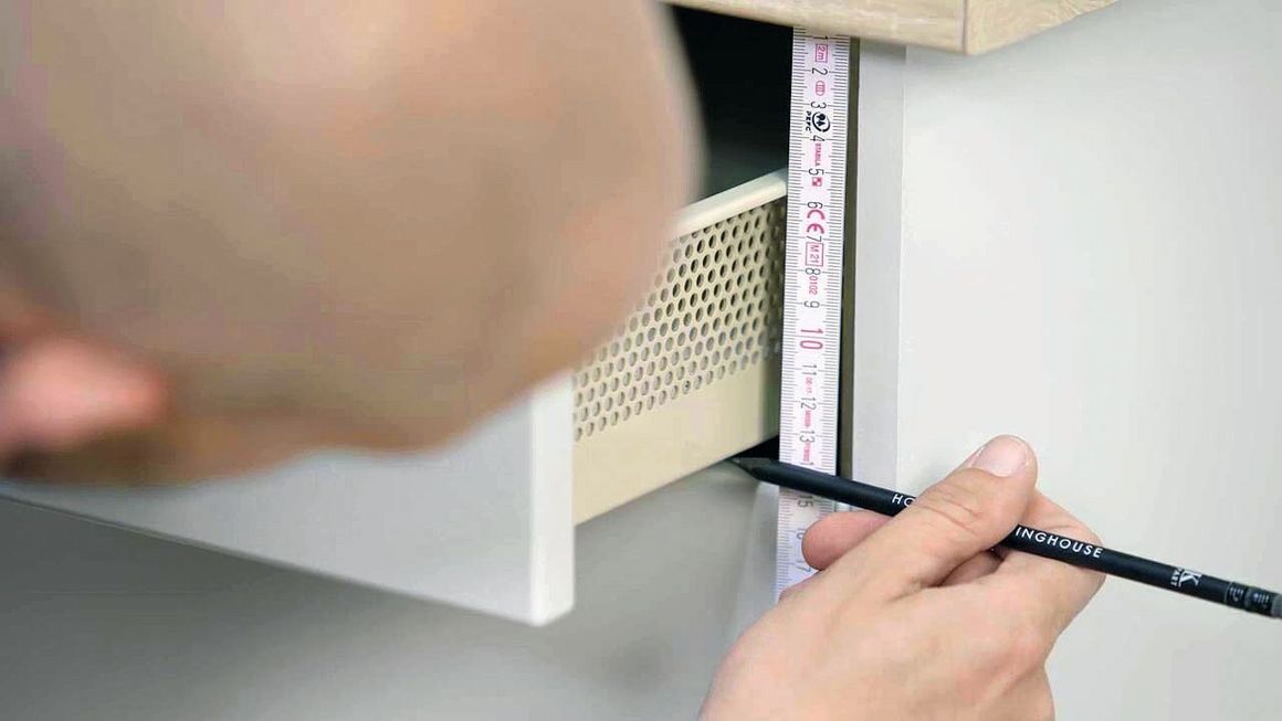 Der Handwerker vermisst die Höhe der eingesetzten Schublade.