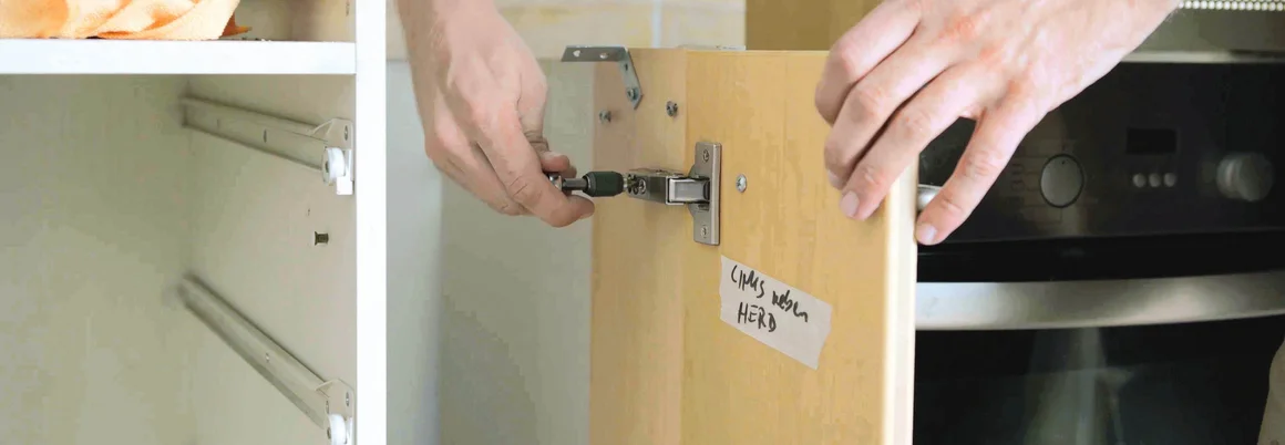 Person montiert Schranktür mit Akkuschrauber.