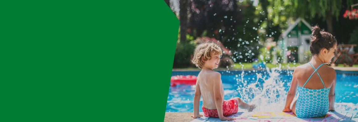 Zwei Kinder sitzen am Pool und planschen mit Wasser.
