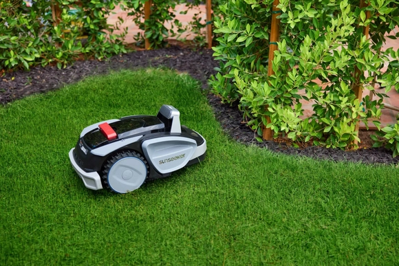 Ein Mähroboter steht auf einem gepflegten, grünen Rasen.