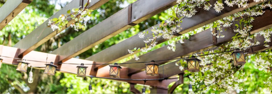 Holzpergola mit Lichterkette und Blüten