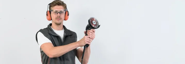 Person mit Schutzbrille und Winkelschleifer