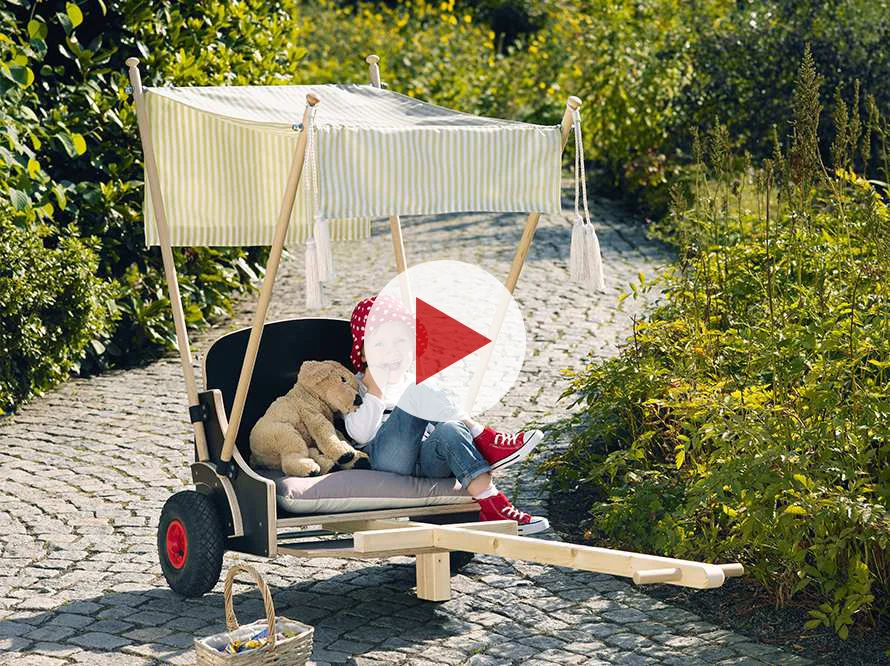 Kind sitzt in kleinem Wagen mit Stoffverdeck