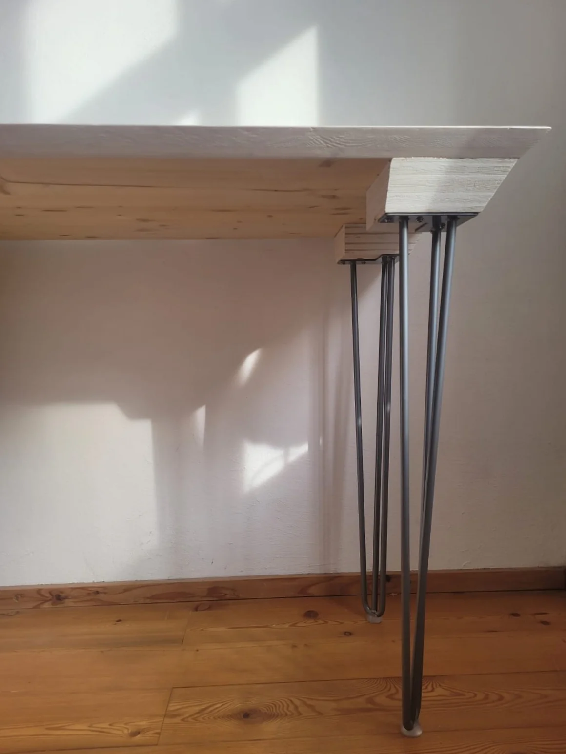 Detailaufnahme eines Holztisches mit Haarnadelbeinen.